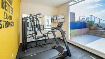 A gym with a treadmill, weight machine, and motivational wall.
