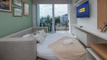 A modern living room with a sofa, a TV, and a balcony with a table and chairs.