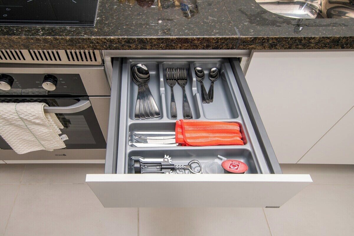 A kitchen drawer with utensils and a red cloth.