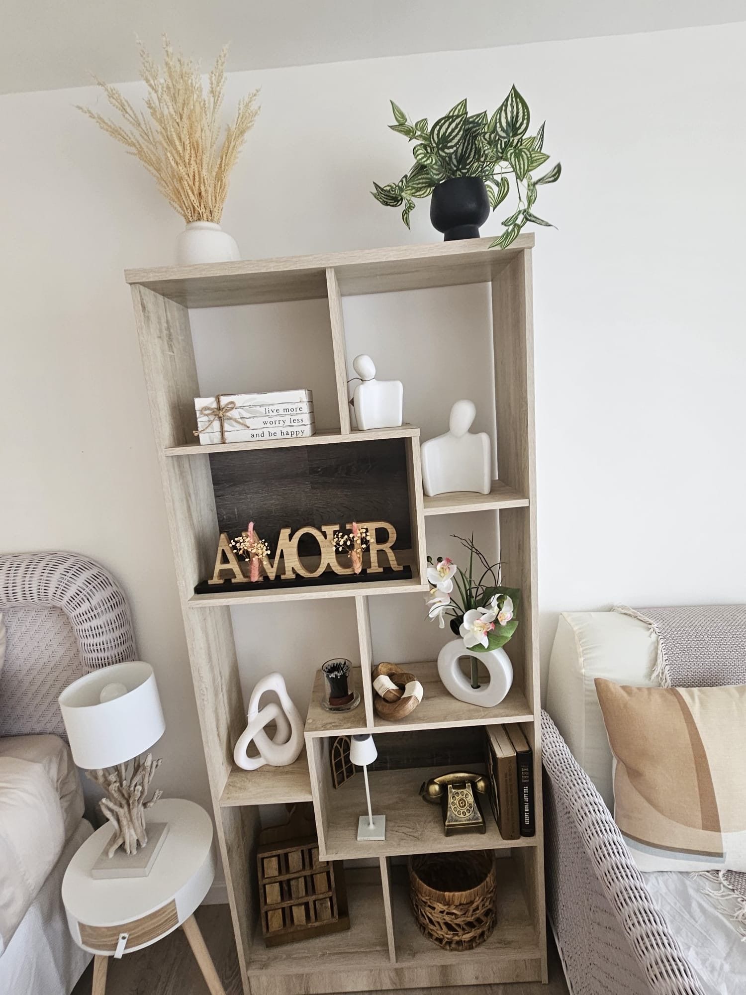Ein Holzregal mit verschiedenen Dekorationselementen, darunter ein Schild mit der Aufschrift 'AMOUR', eine kleine Pflanze und eine weiße Vase.