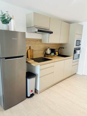 A modern kitchen with a stainless steel refrigerator, a built-in oven, and a microwave. - Bohemian studio just a stone's throw from the beach (Mont vernon)