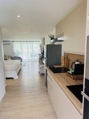 A modern kitchen with a black refrigerator, wooden countertop, and a dining area with a table and chairs. - Bohemian studio just a stone's throw from the beach (Mont vernon)