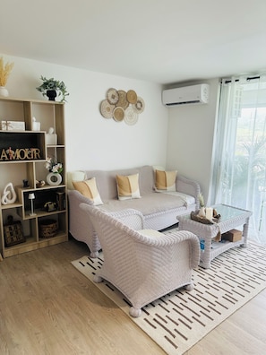 A living room with a sofa, a coffee table, a bookshelf, and a decorative wall piece. - Bohemian studio just a stone's throw from the beach (Mont vernon)