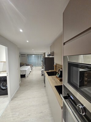 A modern hotel room with a kitchenette, a dining area, and a separate bedroom. - Bohemian studio just a stone's throw from the beach (Mont vernon)