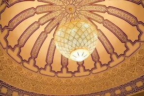 A detailed ceiling with geometric patterns and a central light fixture.