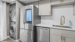 Une cuisine moderne dotée d’appareils électroménagers en acier inoxydable, d’un lave-linge encastré et d’un dosseret décoré d’un motif en chevrons.