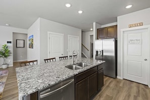 A modern kitchen with a granite countertop, stainless steel appliances, and a wooden dining area. - Large 2 bedroom home with AC in Colorado Springs (Colorado Springs)