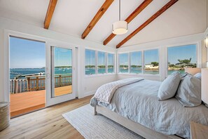Un dormitorio con una cama grande, varias ventanas y vistas al mar.