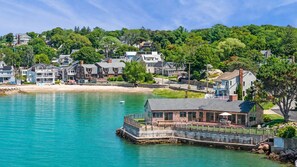 A coastal town with a dock extending into turquoise waters, surrounded by residential buildings and lush greenery. - Stay at Windward Point (Gloucester)