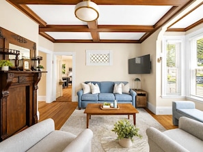 A living room with a blue sofa, wooden coffee table, and a fireplace with a mantel.