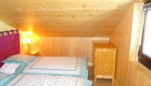 A room with a bed, a nightstand, a wooden cabinet, and a window. - 3rd floor, view village, balcony, tv, ski locker, 58m², Les Gets (Les Gets)