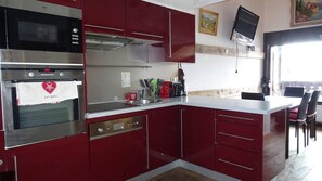 A kitchen with red cabinets, a stainless steel oven, a microwave, and a coffee maker. - 3rd floor, view village, balcony, tv, ski locker, 58m², Les Gets (Les Gets)