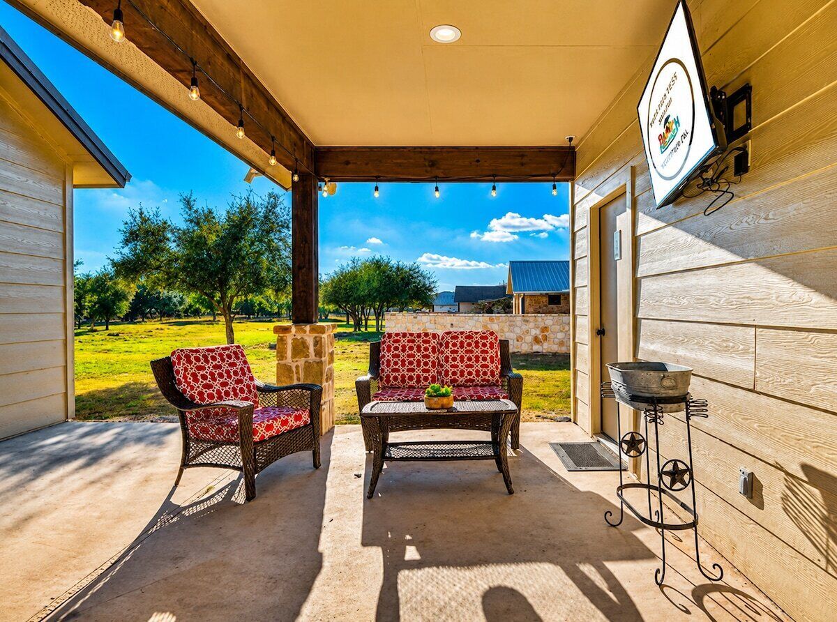 An outdoor patio with wicker furniture, a stone wall, and a view of a green landscape.
