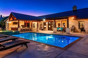 Ein Poolbereich mit einem Steinhaus, Sitzgelegenheiten im Freien und einem klaren, blauen Pool.