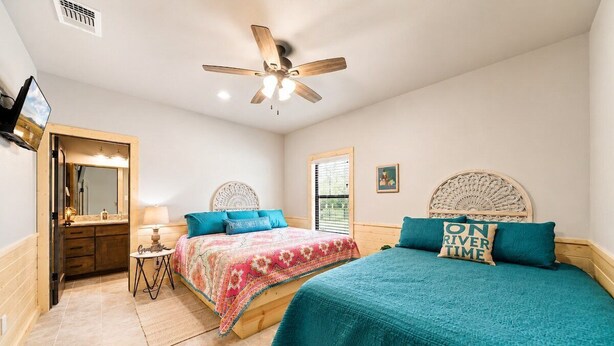 A bedroom with two beds, a ceiling fan, a mirror, and a window. - Spacious Lodge w/ Pool & Hot Tub Near Frio River (Concan)
