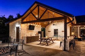 Ein Gebäude aus Stein mit einem Holzdach, Sitzgelegenheiten im Freien und einer Bar.