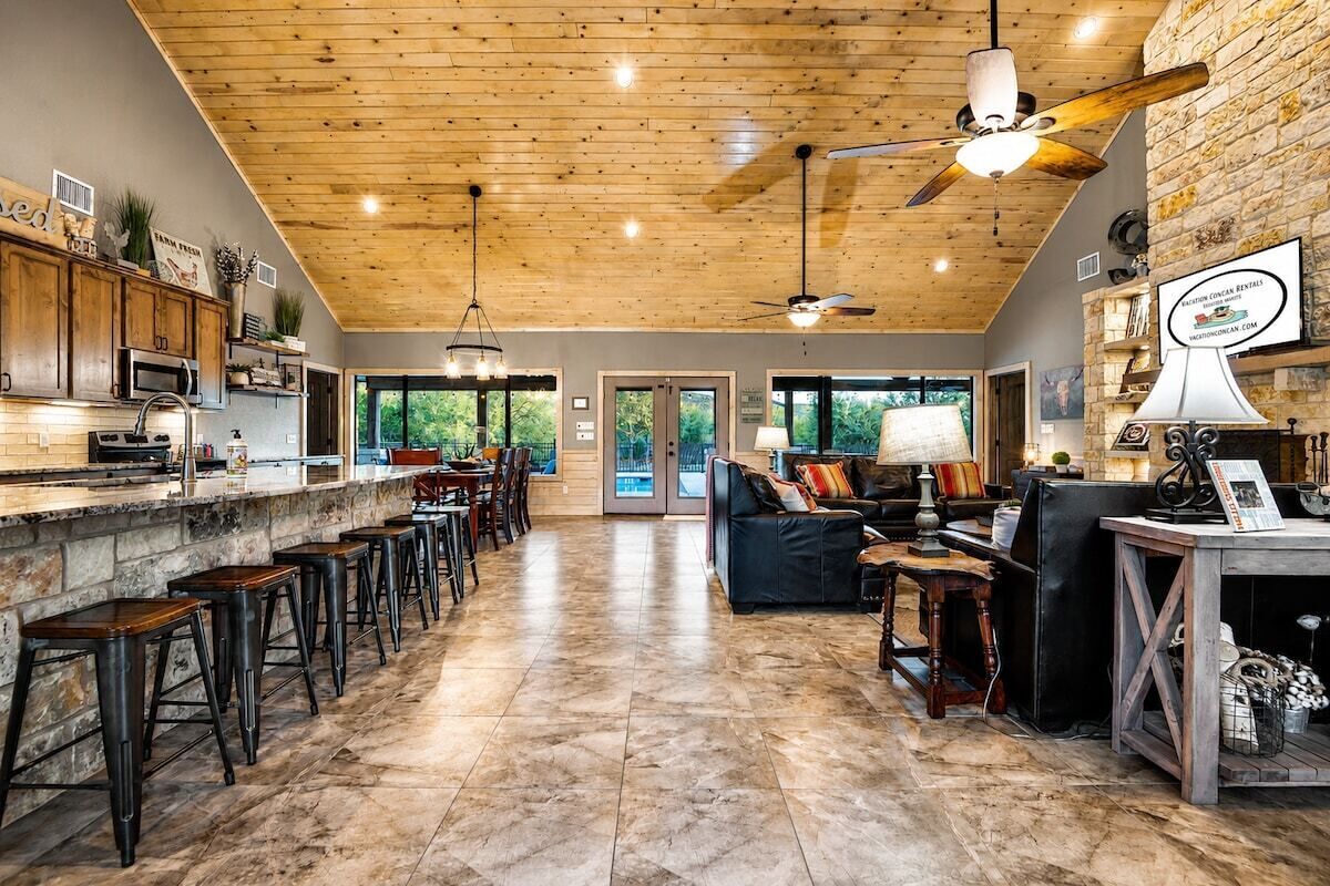Een ruime keuken met een bar, houten plafond en grote ramen.