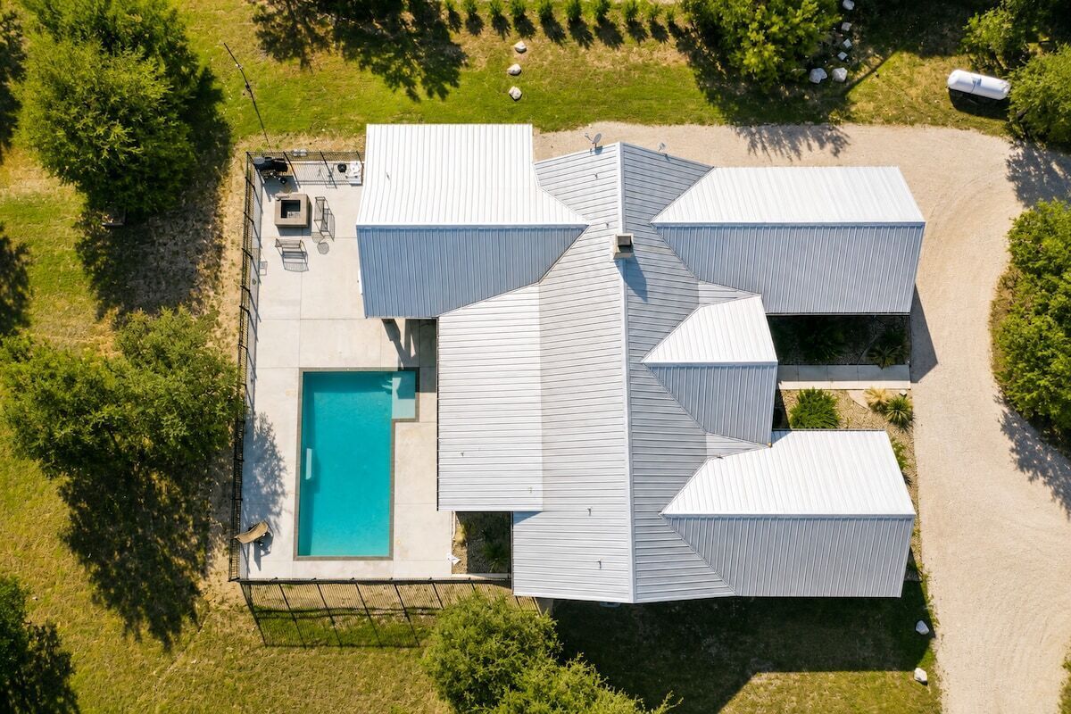 Une maison moderne dotée d’une piscine, entourée d’une pelouse bien entretenue et d’arbres.