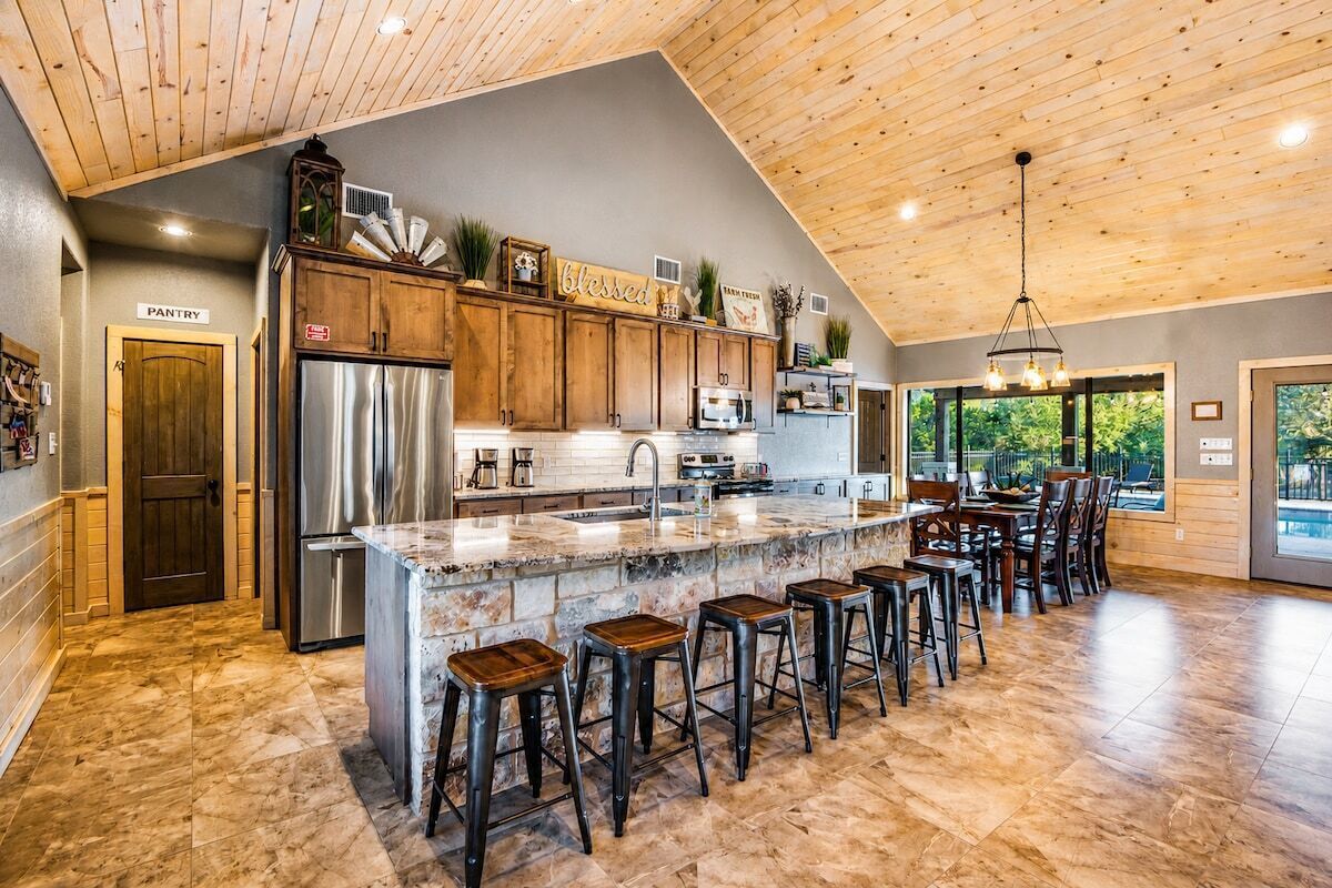 A spacious kitchen with a large island, wooden cabinets, and a bar area with stools.