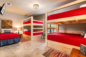 A room with bunk beds, a desk, and a chair. There is a window with a view of trees. - Chula Vista 6BR Home with Heated Pool and BBQ (Sabinal)