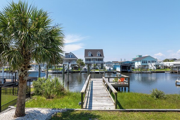A waterfront property with a dock, boats, and a large house with a balcony. - Canalfront dock and screened porch (Surf City)