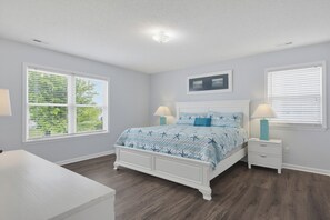A bedroom with a bed, two bedside tables, a nightstand, a window with blinds, a ceiling light, and a wall-mounted picture. - Canalfront dock and screened porch (Surf City)