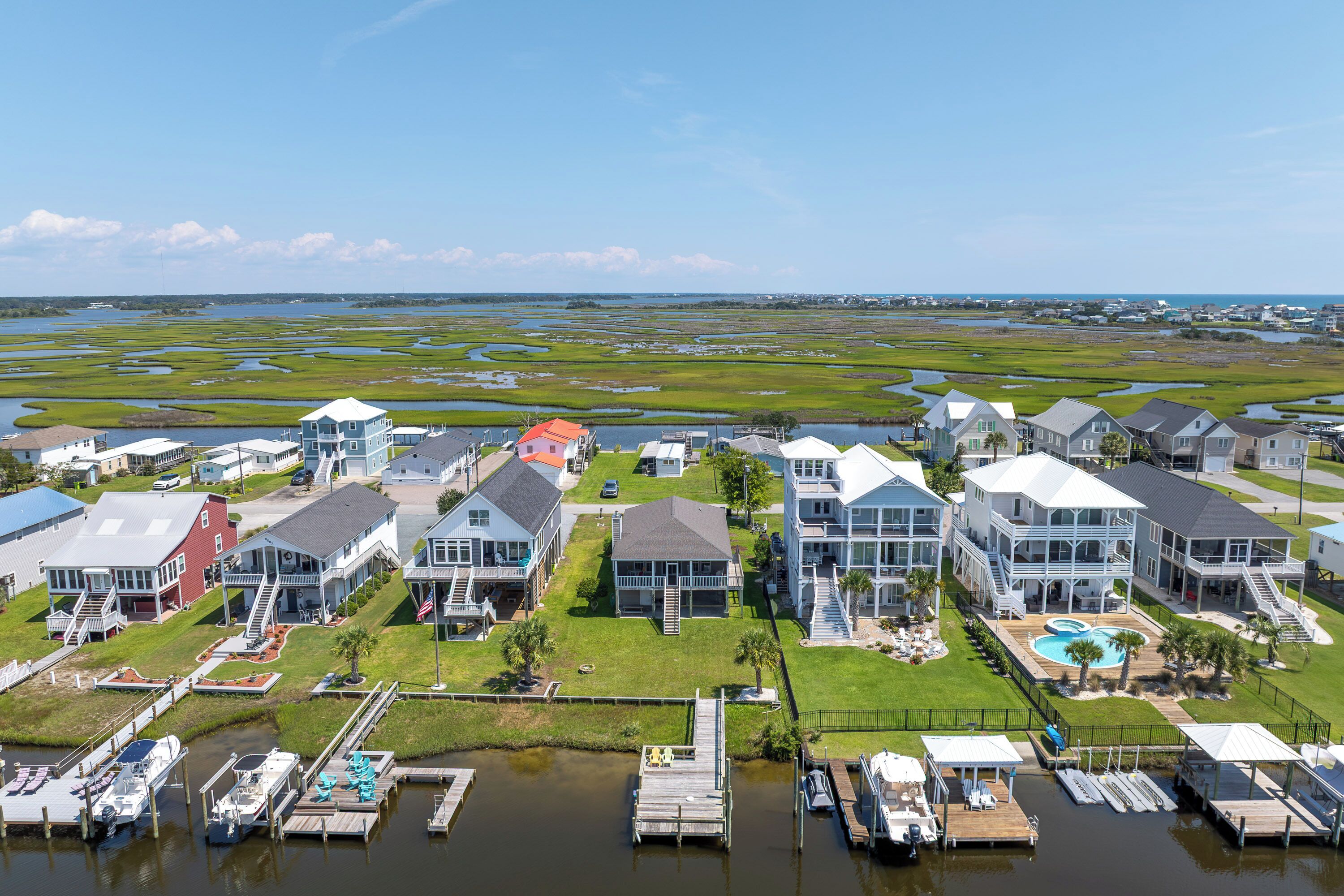 Een kustgebied met woningen, een jachthaven en een moerachtig landschap.