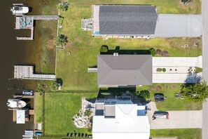 A residential area with a dock, a house with a sloped roof, and a lawn. - Canalfront dock and screened porch (Surf City)