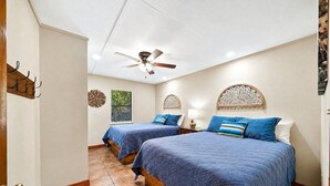 Ein Hotelzimmer mit zwei Betten, einem Deckenventilator und Wanddekoration.