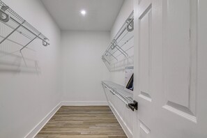 Una sala de bugaderia amb estands metàl·lics per estendre la roba, un terra de fusta i una porta blanca.