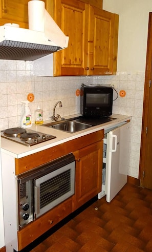 Eine kleine Küche mit Mikrowelle, Herd, Backofen und kleinem Kühlschrank.