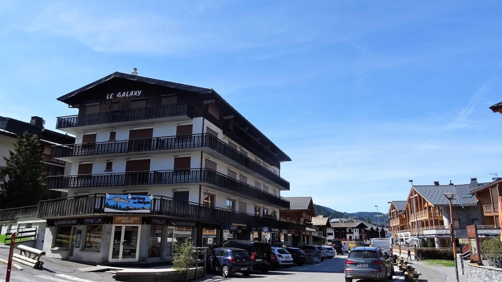 A multi-story hotel with balconies, a restaurant, and a parking area.