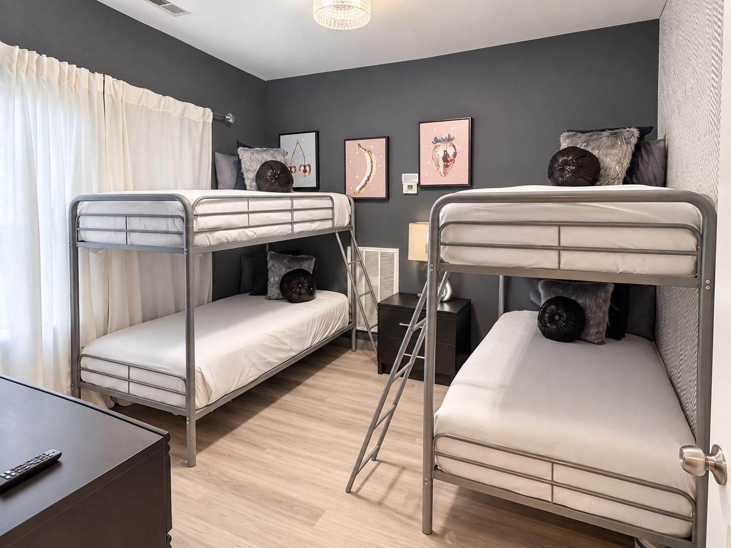 A bunk bed room with a desk, a lamp, and artwork on the walls.