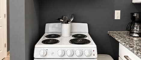 Una cocina con estufa blanca, un microondas arriba y un reloj en la pared.