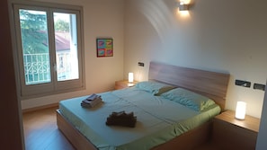 Een slaapkamer met een bed, twee nachtkastjes, een raam en een wandlamp.