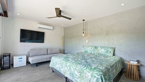 A modern bedroom with a bed, a sofa, an air conditioning unit, and a ceiling fan. - Luxury Villa + Casita in Mar Vista (Playa Brasilito)