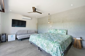 Ein modernes Schlafzimmer mit Bett, Sofa, Klimaanlage und Deckenventilator.