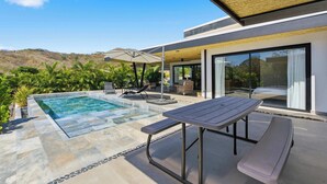A modern outdoor pool area with a stone border, lounge chairs, and a table. - Luxury Villa + Casita in Mar Vista (Playa Brasilito)