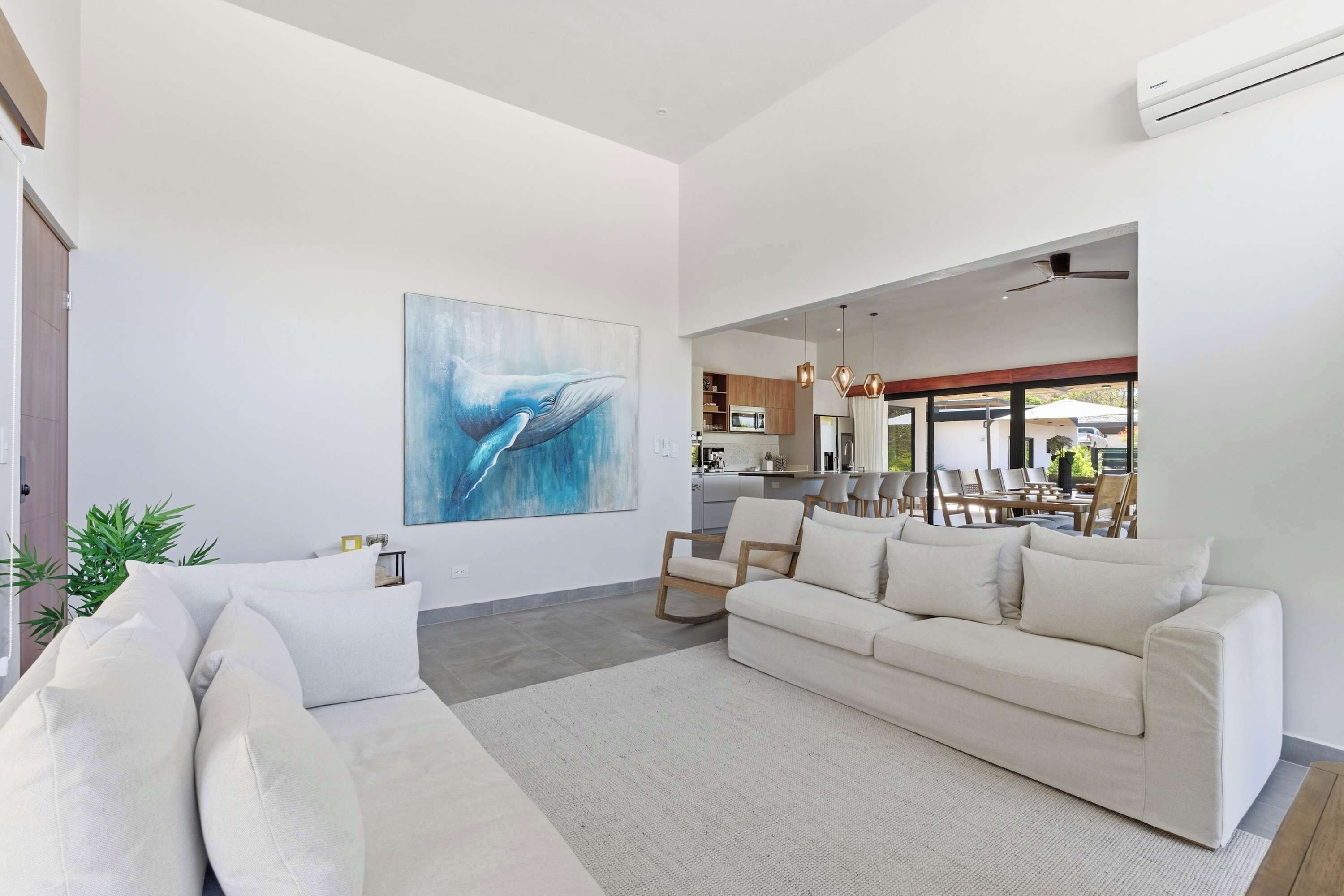 A modern living room with a large painting, a sofa, and a dining area with chairs.