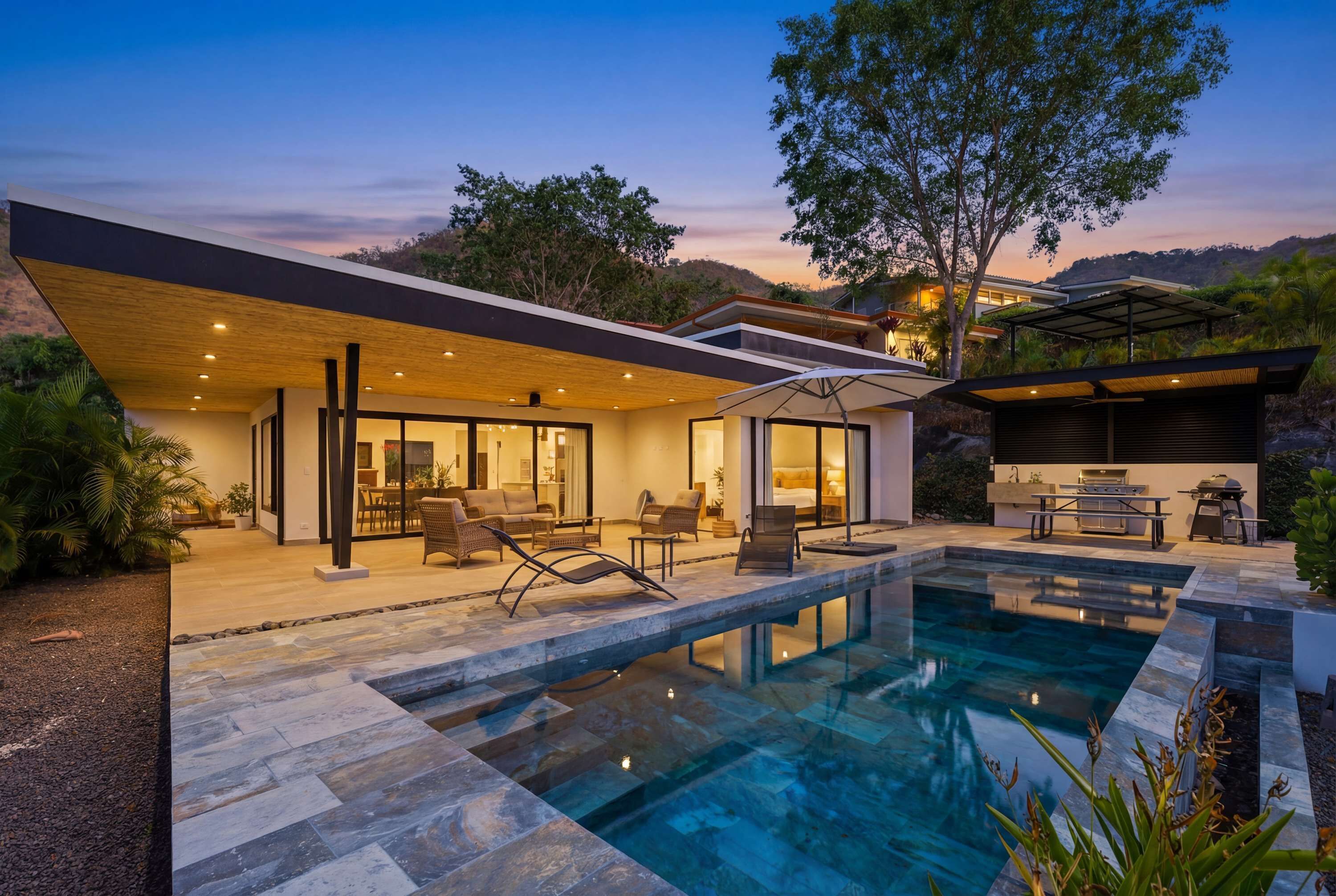 A modern house with a swimming pool, outdoor furniture, and a patio area.