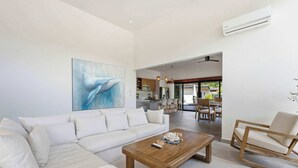 A modern living room with a sofa, a coffee table, and a dining area with chairs and a table. - Luxury Villa + Casita in Mar Vista (Playa Brasilito)
