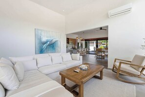 Ein modernes Wohnzimmer mit einer Couch, einem Couchtisch und einem Essbereich mit Stühlen und einem Tisch.