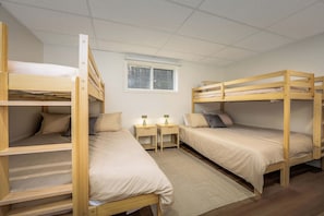 Ein Schlafsaalzimmer mit Etagenbetten, einem kleinen Fenster und Nachttischen mit Lampen.
