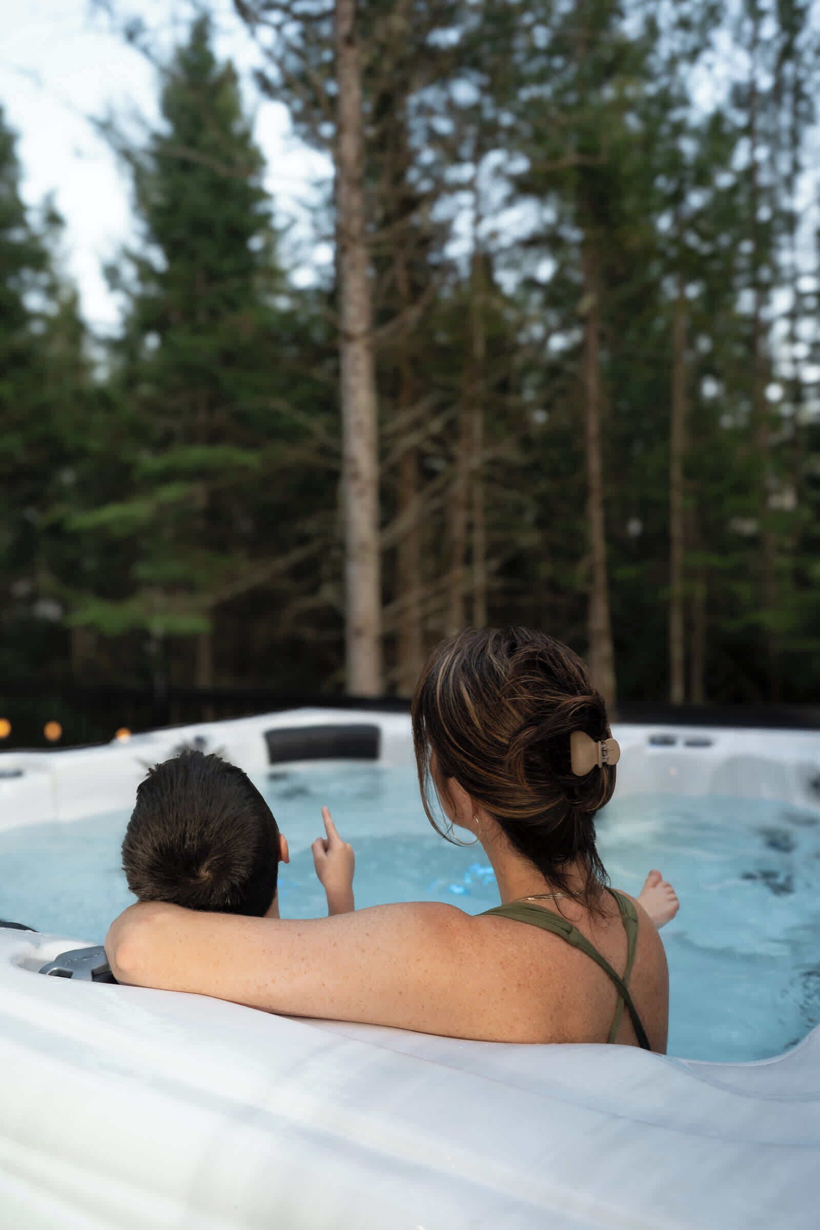 A hot tub in a natural setting with tall trees in the background.