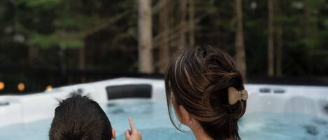 A hot tub in a natural setting with tall trees in the background.