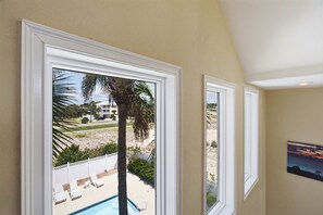 A room with a view of a swimming pool, palm trees, and a building in the background. - Sea Dawg Pool Elevator, Gulf view (Saint George Island)
