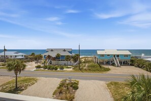 A beachfront property with multiple buildings, including a main house with a blue roof and a smaller structure with a white roof. There is a sandy beach area with palm trees and a clear view of the ocean. - Sea Dawg Pool Elevator, Gulf view (Saint George Island)
