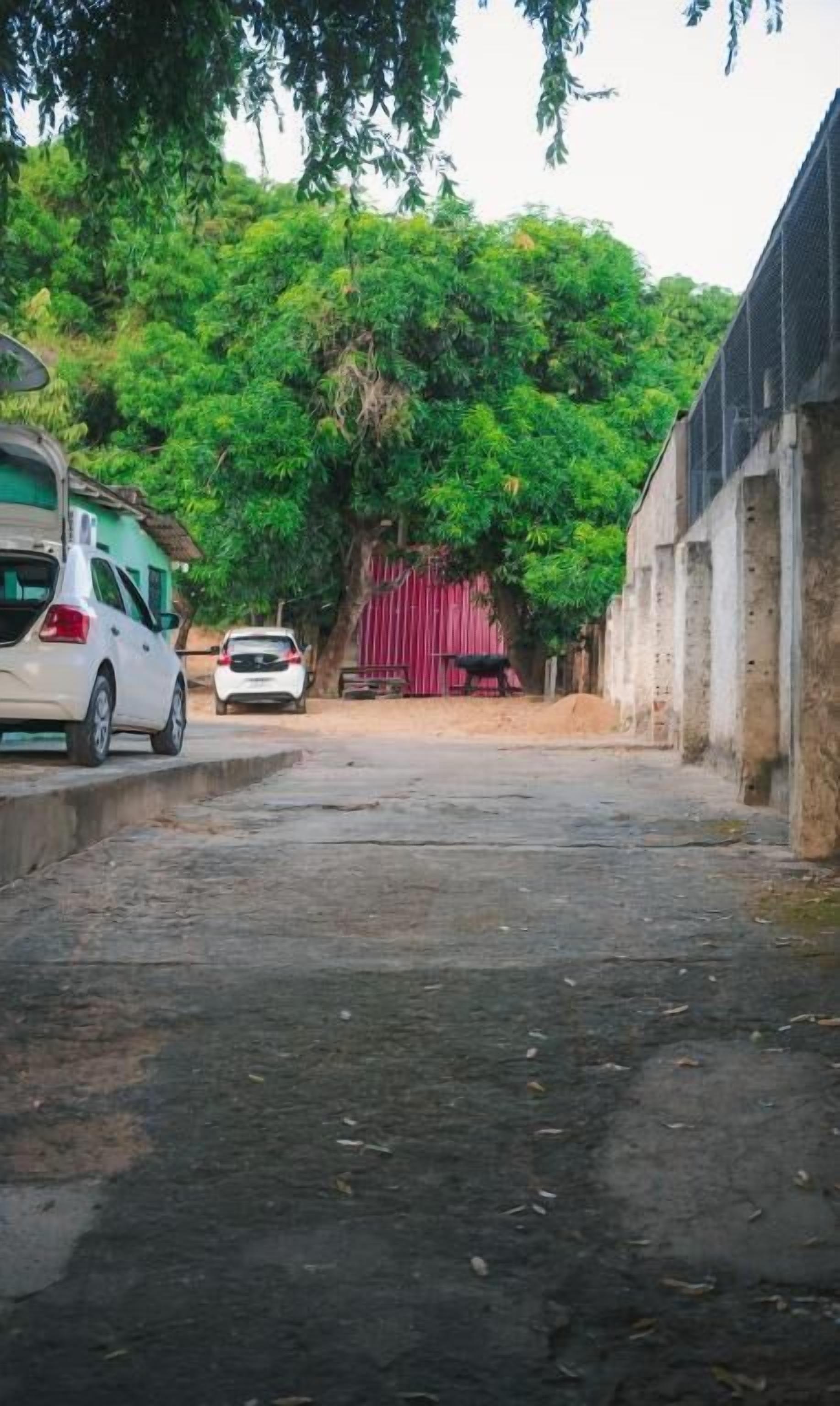 A narrow street with parked cars and a building with a red door.