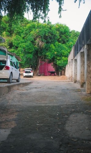 A narrow street with parked cars and a building with a red door.