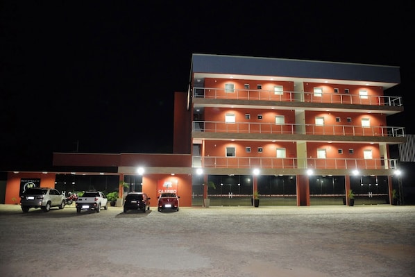 A multi-story hotel with a flat roof and a parking area in front.